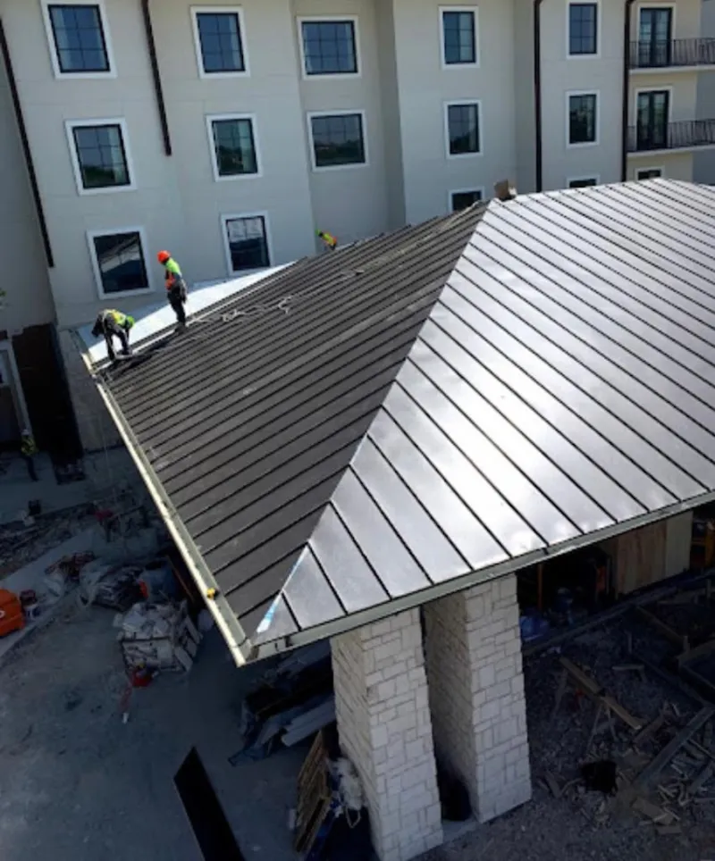 Crew installing standing seam metal roof panels on a commercial project in Gunnison